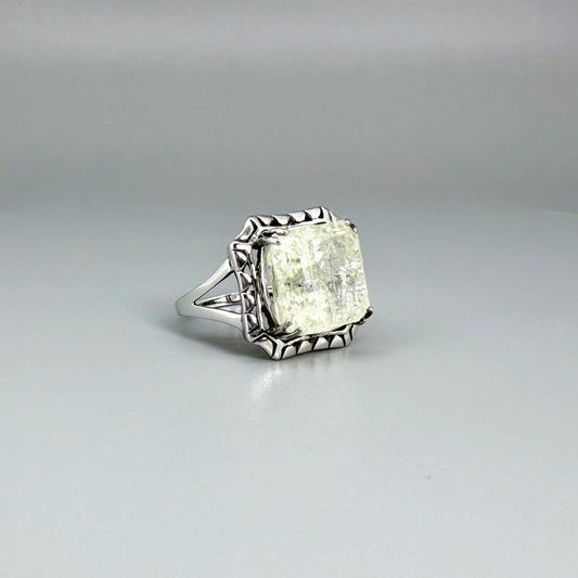 White gold plated sterling silver ring with natural light green emerald, detailed setting, and elegant, refined craftsmanship.