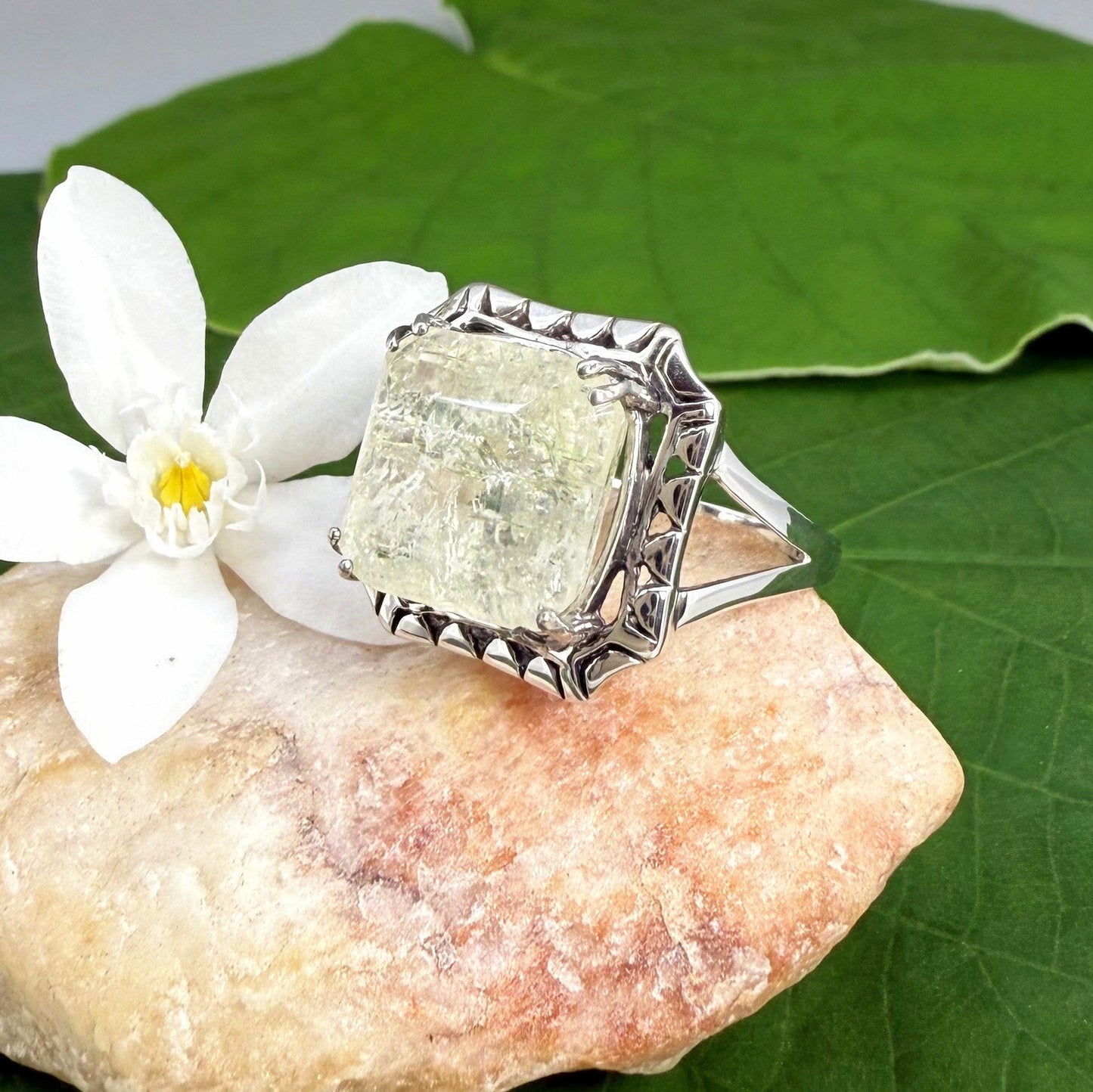 White gold plated sterling silver ring with natural light green emerald, detailed setting, and elegant, refined craftsmanship.