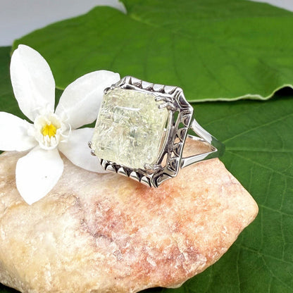 White gold plated sterling silver ring with natural light green emerald, detailed setting, and elegant, refined craftsmanship.