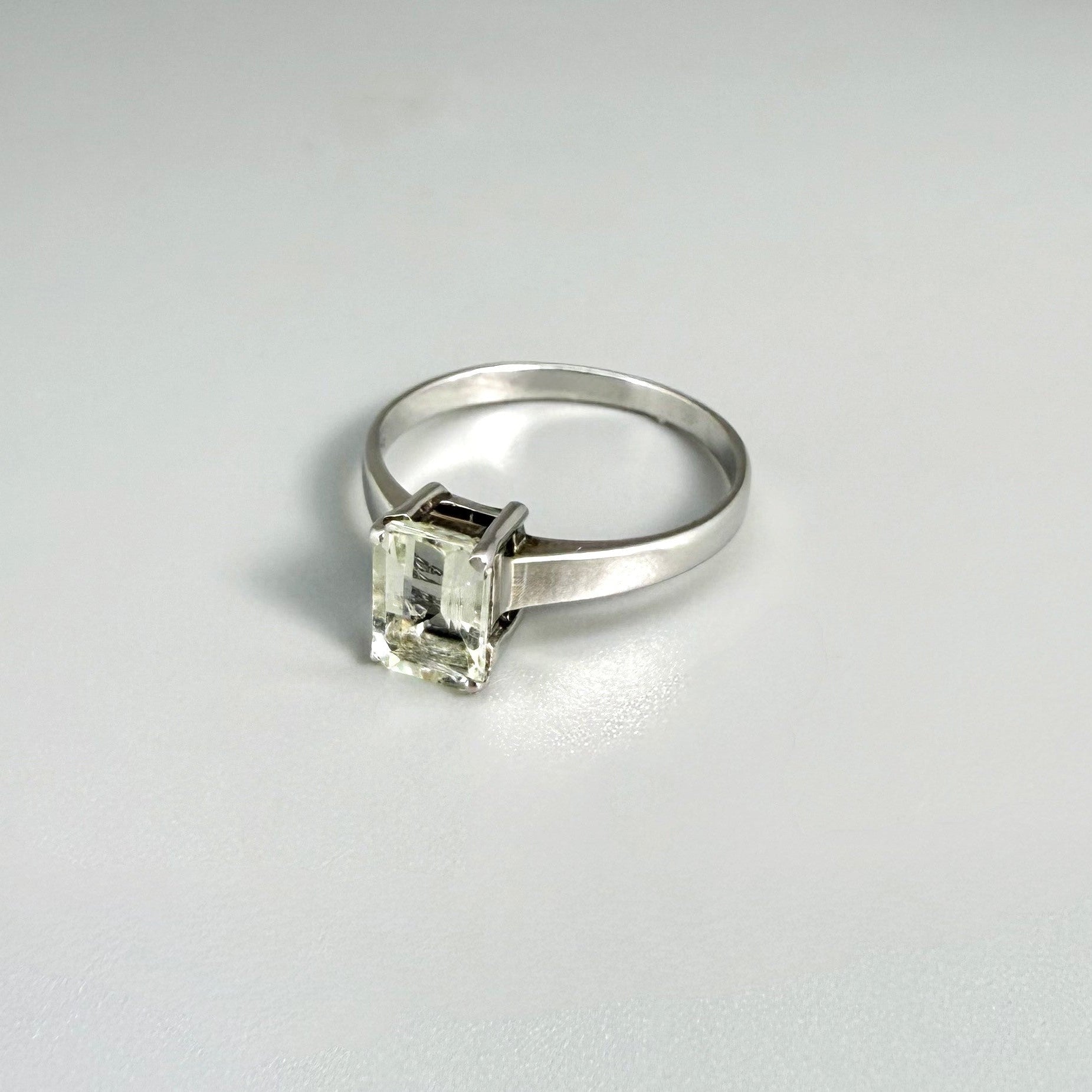 Aquamarine solitaire ring in white gold plated sterling silver, featuring a light blue natural gemstone on neutral background, elegant and timeless design.