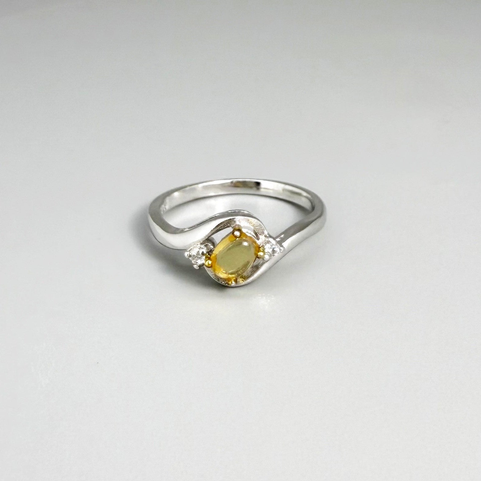 Opal solitaire ring in white gold plated sterling silver, featuring a natural gemstone with yellow hues, elegant and timeless design.