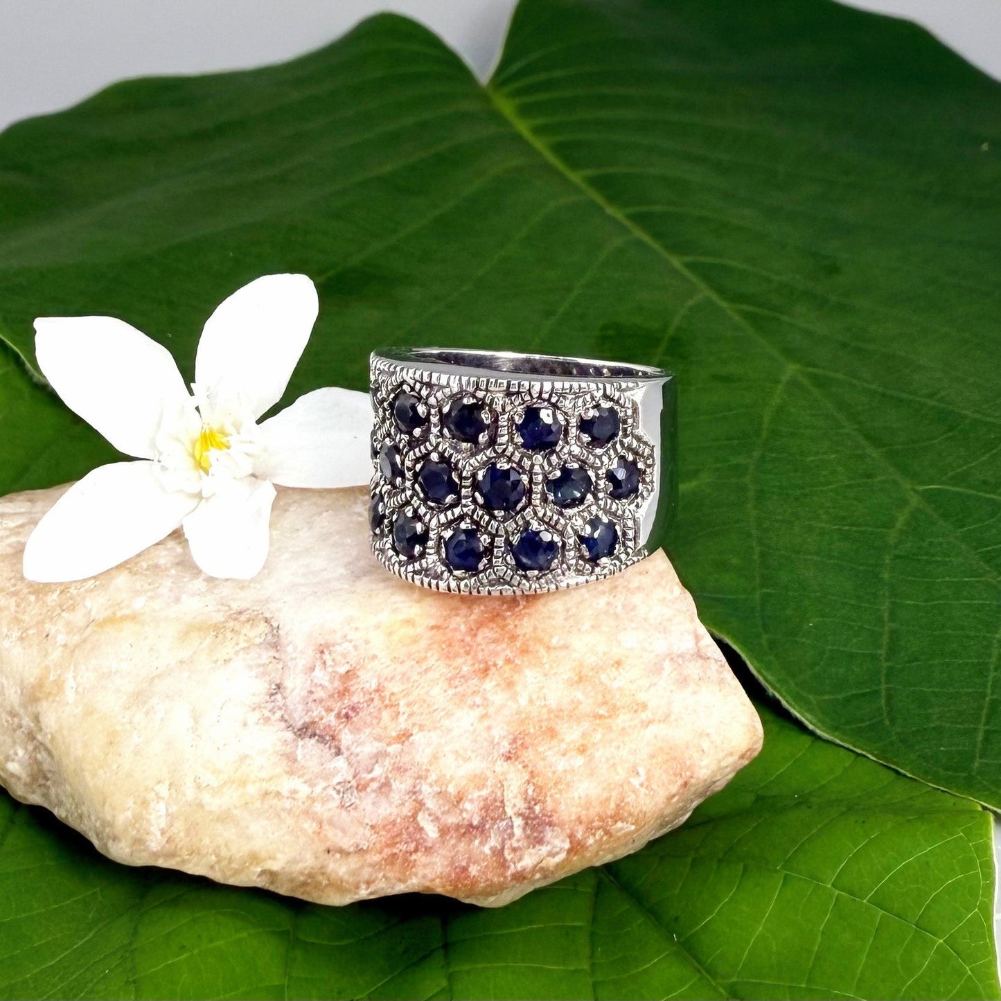 Wide band blue sapphire ring in white gold plated sterling silver featuring faceted deep blue sapphires for an elegant, timeless look.
