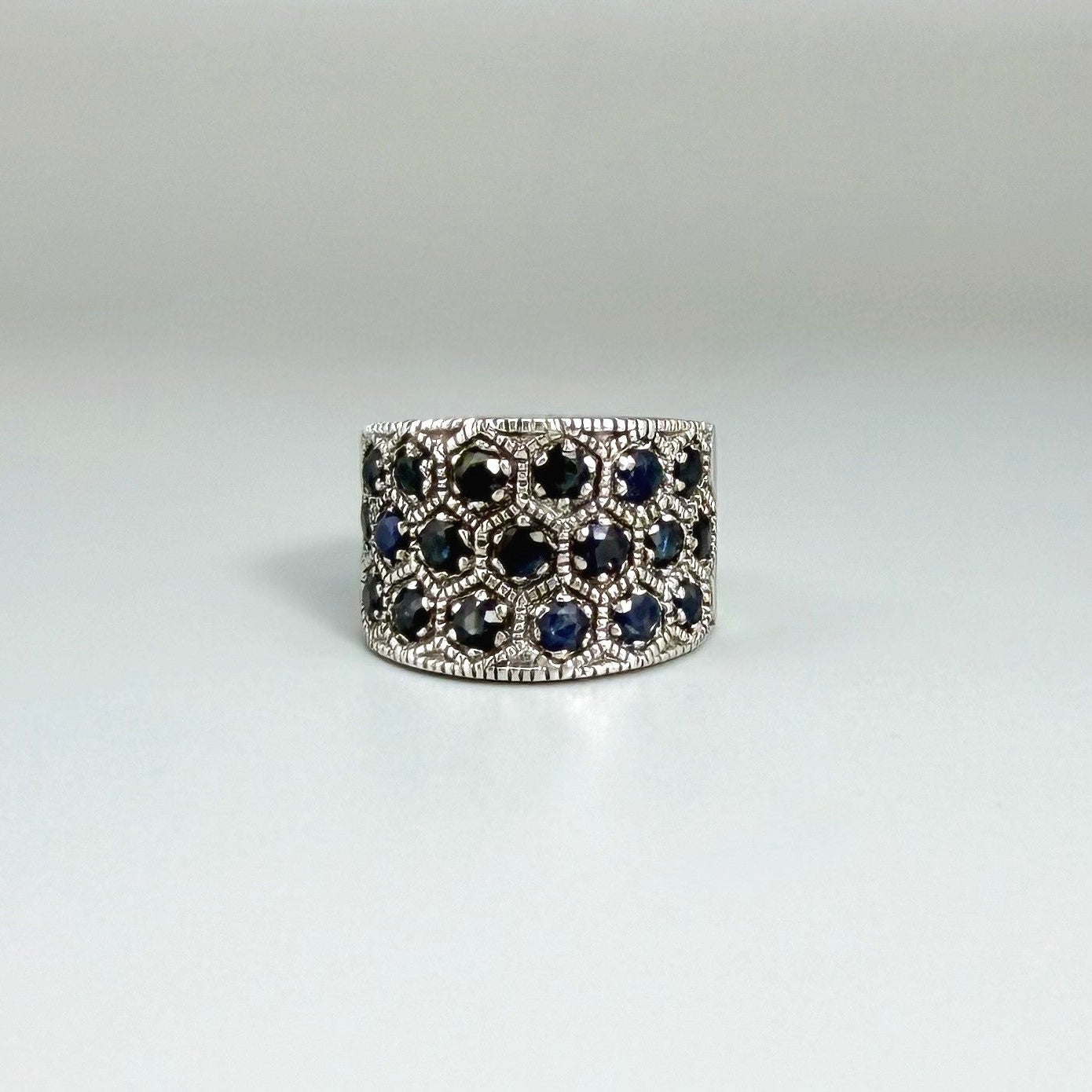 Wide band blue sapphire ring in white gold plated sterling silver featuring faceted deep blue sapphires for an elegant, timeless look.