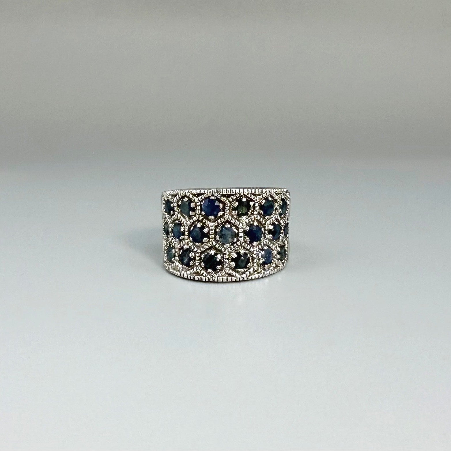 Wide band ring with light blue sapphires set in white gold plated sterling silver, reflecting soft blue brilliance with timeless elegance.