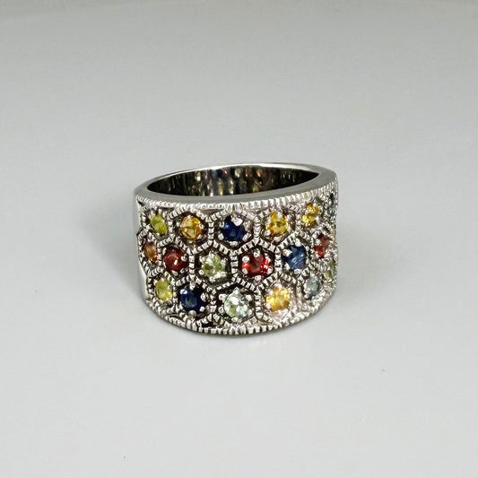 Multicolor sapphire band ring in white gold plated sterling silver, featuring faceted blue, yellow, pink, green, and orange gemstones, elegant wide design.