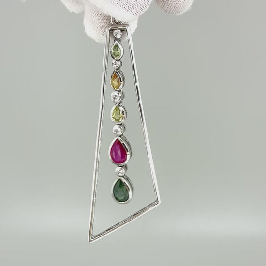 Handmade white gold plated silver pendant featuring 1.97 ct sapphires and 1.32 ct rubies in a modern geometric design with a freely moving gemstone strand.
