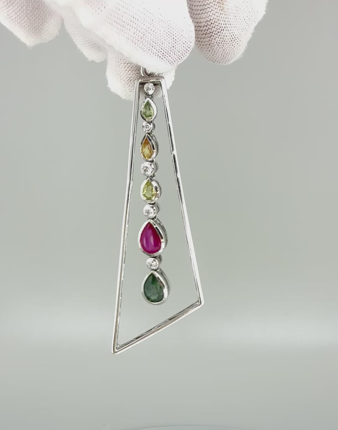 Handmade white gold plated silver pendant featuring 1.97 ct sapphires and 1.32 ct rubies in a modern geometric design with a freely moving gemstone strand.